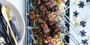 Green papaya salad used as a bed for grilled pork skewers.