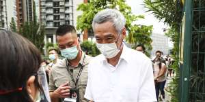 Singapore Prime Minister Lee Hsien Loong wearing a mask,which is mandatory in the island nation,shows his ID before voting last year.