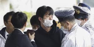 A man,centre,who threw what appeared to be a smoke bomb,is caught at a port in Wakayama,western Japan on Saturday.