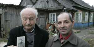 Alex Kurzem (left) with Erik Galperin in front of the Galperin family’s pre-war house in Belarus in 2007. Kurzem,holding a photo of Erik’s father Solomon,believed he and Erik were half-brothers.