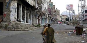 Men ride through streets wrecked by fighting in Taiz,Yemen in this February.