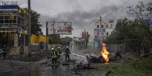 Rescue workers put out the fire of a destroyed car after a Russian attack in a residential area in Kharkiv.