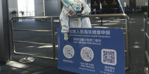 A worker in protective gear points out a QR code to scan to make health declarations for inbound travellers arriving at Guangzhou Baiyun Airport in southern China’s Guangdong.