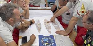 Scuba divers study a map of the sailing yacht Bayesian at the Porticello harbor.