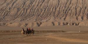 Tourists on camels at the Flaming Mountains in Turpan.