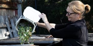 Marika Nabung empties her compost bin into the large compost at a community garden in Rose Bay,
