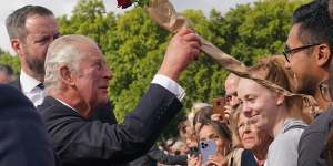 Charles accepts a rose from well-wishers during a walk outside Buckingham Palace.