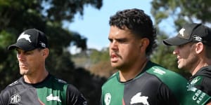 Rabbitohs assistant coaches John Morris and Ben Hornby look at training as Latrell Mitchell jogs by.