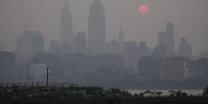 The sun rises over a hazy New York City skyline.