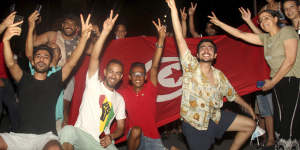 Demonstrators celebrate with a Tunisian national flag during a rally after the president suspended the legislature and fired the prime minister in Tunis,Tunisia.