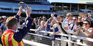 James McDonald holds his Everest trophy towards the crowd after winning on Nature Strip in 2021.