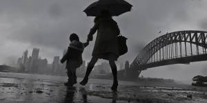 A woman and child walk through Kirribilli as the rain hit Sydney again on Thursday.
