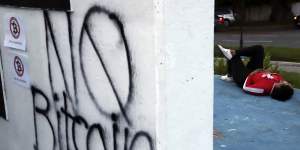 A woman rests near a wall spray painted with a “No Bitcoin” message during an anti-government protest in San Salvador.