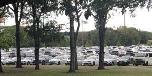 Cars parked on fields near Kippax Lake at Moore Park during an event.