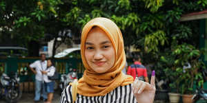 Putri Elma,a first-time voter,shows the inked finger proving she has already cast her ballot.