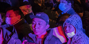 Protesters march by a police in Beijing. 