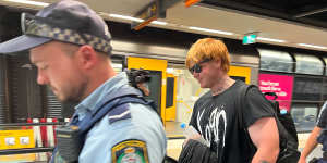 Police escort a man out of North Sydney station on Friday afternoon.