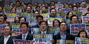 Kwon Sung-dong,floor leader of the People’s Power Party,front centre,and MPs chant slogans and hold placards after a vote on an impeachment motion against South Korean acting president Han Duck-soo at the National Assembly in Seoul on Friday.