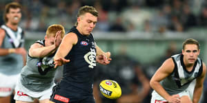 Patrick Cripps of the Blues kicks whilst being tackled by Willem Drew of the Power.