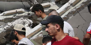 Palestinian emergency services and local citizens search for victims in buildings destroyed during Israeli air raids.
