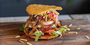 A crisp fried arepa split into two discs hosts a variety of burger fillings.