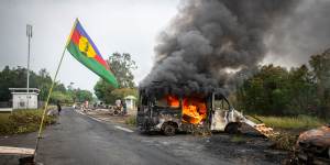 A Kanak flag waving next to a burning vehicle at a roadblock at La Tamoa,in the commune of Paita in New Caledonia.