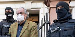 Masked police officers lead Heinrich XIII Prince Reuss to a police vehicle during a raid against so-called “Reich citizens” in Frankfurt,Germany,on Wednesday.