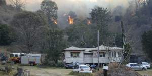 Fire and Emergency crews battle a bushfire near a house in the town of Canungra.
