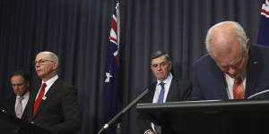 (From left) Greg Hunt,Professor Paul Kelly and Professor Brendan Murphy with Prime Minister Scott Morrison,who is taking a closer look at his notes during a press conference on Thursday night.