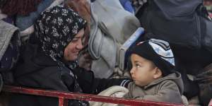 Displaced Palestinians gather with their belongings near a roadblock on Salah al-Din Street,as they wait.