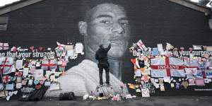 Street artist Akse P19 repairs the defaced mural of Manchester United striker and England player Marcus Rashford.