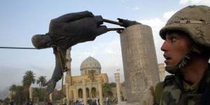 A US soldier watches as a statue of Iraq's President Saddam Hussein falls in central Baghdad in 2003. 