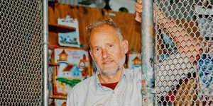 Steve Keene in his home workspace,a studio encircled in chain-link fencing that he affectionately calls “The Cage”.