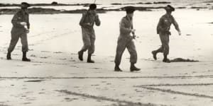 An army search party equipped with two-way radio look for Harold Holt on Cheviot Beach.