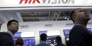 Visitors pass by a booth for state-owned surveillance equipment manufacturer Hikvision at the Security China 2018 expo in Beijing. 