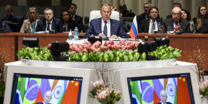 Russia’s Foreign Minister Sergei Lavrov (centre) looks on as Russian President Vladimir Putin delivers his BRICS summit remarks via video link.