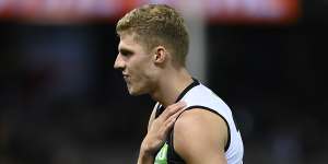 An injured Will Kelly of the Magpies grabs at his collarbone in Friday night’s clash with the Tigers