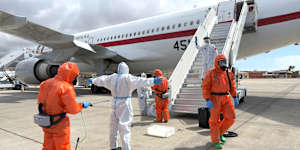 A Spanish passenger is sprayed with disinfectant by Spanish government officials before boarding a plane after disembarking from the hantavirus-stricken cruise ship on Sunday.