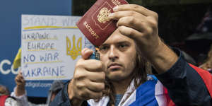 A man draped in the Russian flag attempts to burn a passport during the Stop War in Ukraine rally.