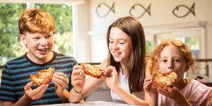 Charlie,14,Sophie,12,and Lucy,6,eating a new McCain vegemite pizza.
