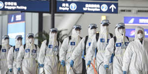 Chinese firefighters in Wuhan,2020,prepare to disinfect an incoming plane. The Reserve Bank created hundreds of billions of dollars to protect the economy from the pandemic’s impact.