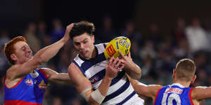 Oliver Henry of the Cats marks the ball in between Ed Richards of the Bulldogs and Liam Jones of the Bulldogs.