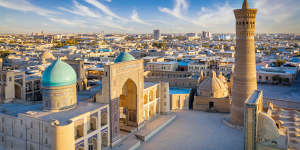 Aerial view down towards the famous Kalyan Poi Kalon Complex and Poi Kalon Minaret,Poi Kalan or Po-i-Kalyan and Mir Arab Madrasah (right side) in the center of the old town of Bukhara - Buxoro - Бухорo on a sunny day. Aerial Drone Point view at Sunset. Itchan Kala,Bukhara,Khorezm Region,Uzbekistan,Central Asia. 