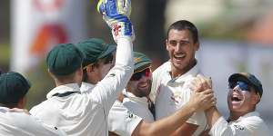 Australia's Mitchell Starc celebrates with teammates after taking a wicket with the first ball.