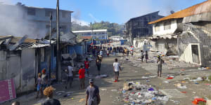 People walk through the looted streets of Chinatown in Honiara on November 26.