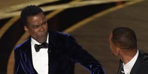 Chris Rock,left,reacts after being hit on stage by Will Smith while presenting the award for best documentary feature.