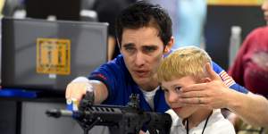 A boy is shown how to sight down an electronic rifle during the National Rifle Association's annual meeting in Nashville.