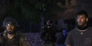 Jewish right-wing demonstrator holds a rock as he stand by Israeli paramilitary border police during clashes between Arabs,police and Jews,in the mixed town of Lod,central Israel.