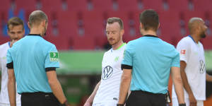 Wolfsburg's Maximilian Arnold taps feet with the referee and his assistant after the match.