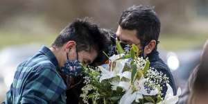 Juan Carlos Rangel,left,hugs his mother Beatriz and father Carlos during Beatriz's father's burial ceremony in Greeley,Colorado. The longtime JBS employee was the first to die of COVID-19 at the JBS meat processing plant. 